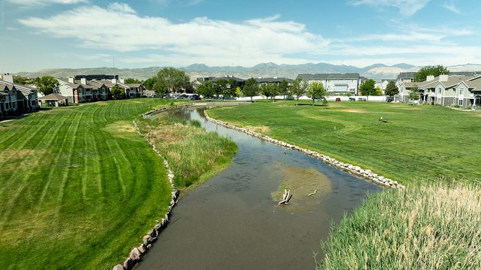 Scenic view of a serene neighborhood with well-maintained green lawns and a tranquil stream, perfect for nature lovers and peaceful living.