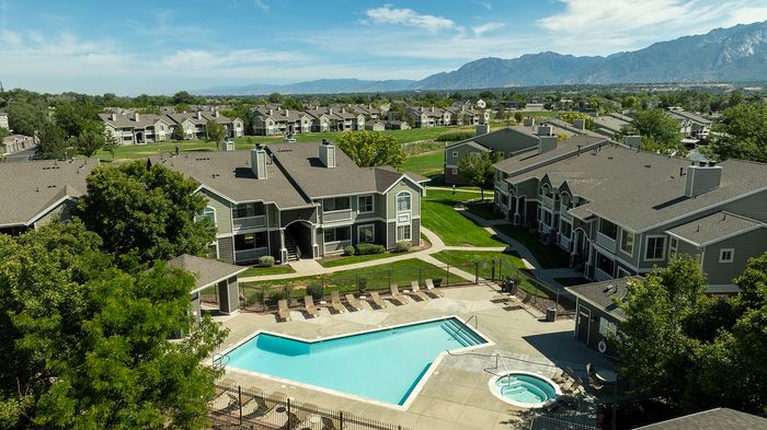 Inviting apartment complex with lush greenery, stunning mountain views, and a sparkling pool perfect for relaxation.
