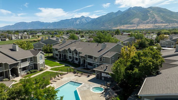 Charming apartment complex with scenic mountain views, featuring lush landscaping and a sparkling pool area.