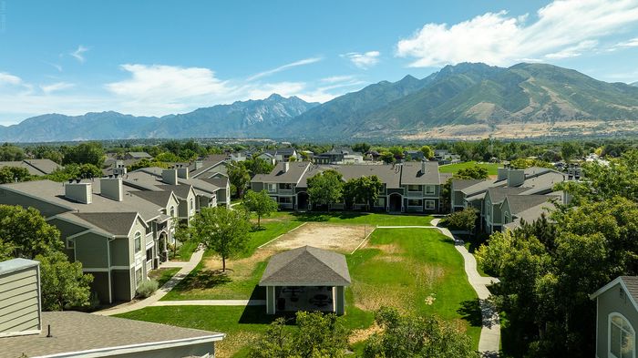 Stunning aerial view of modern apartment complex with manicured lawns and breathtaking mountain backdrop.