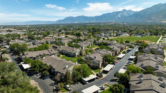 Stunning aerial view of a serene residential community nestled near majestic mountains, showcasing charming homes and lush greenery.