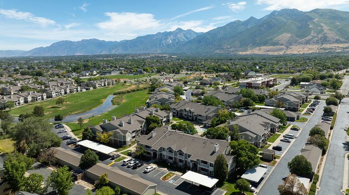 Scenic aerial view of a charming residential community with modern townhouses, lush green spaces, and mountain vistas, offering a serene lifestyle.