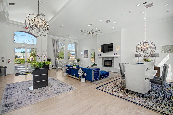 Luxurious apartment lobby with elegant chandeliers, plush blue seating, and a cozy fireplace, offering a welcoming and sophisticated ambiance.