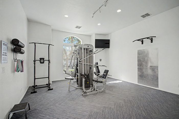 Bright fitness room featuring modern gym equipment, airy design, and ample natural light.