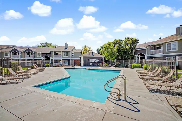 Inviting apartment complex with a pristine swimming pool, surrounded by modern architecture and lush greenery, perfect for relaxation and leisure.