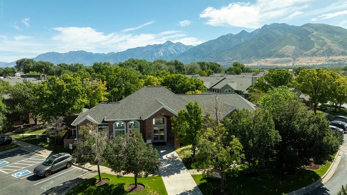 Captivating aerial view of a charming residential complex surrounded by lush greenery and majestic mountains.