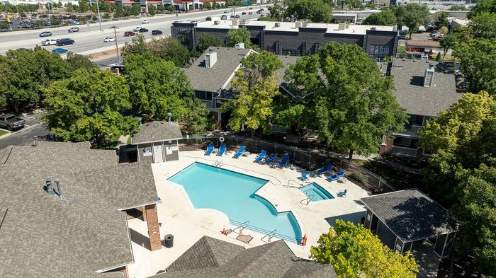 Inviting apartment complex with a refreshing central swimming pool, surrounded by lush greenery and modern buildings for relaxation and leisure.