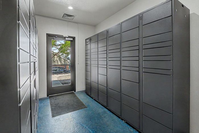 Modern package locker room with sleek metal lockers and natural light entering through a glass door, offering secure convenience.