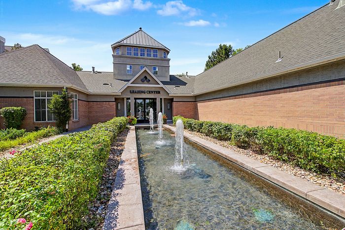 Inviting entrance of the leasing center featuring elegant fountains, lush greenery, and a welcoming architectural design.