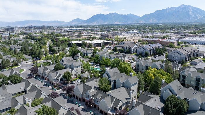 Breathtaking aerial view of a scenic residential community with charming apartment homes, lush greenery, and mountain backdrop.
