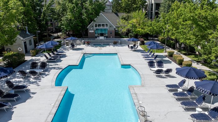 Luxurious outdoor pool area surrounded by lush greenery, stylish lounge chairs, and elegant blue umbrellas, perfect for relaxation and leisure.