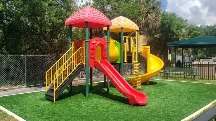 Royalton on The Green Exterior | Green and yellow playground | Gated area | Grass outside gated area