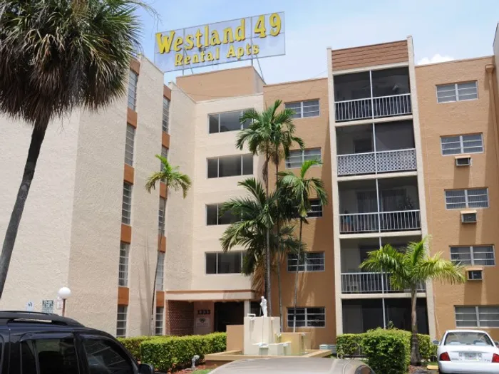 Westland 49 Apartments Exterior | Brown building | 5 stories tall | Sign on top of building | Palm trees