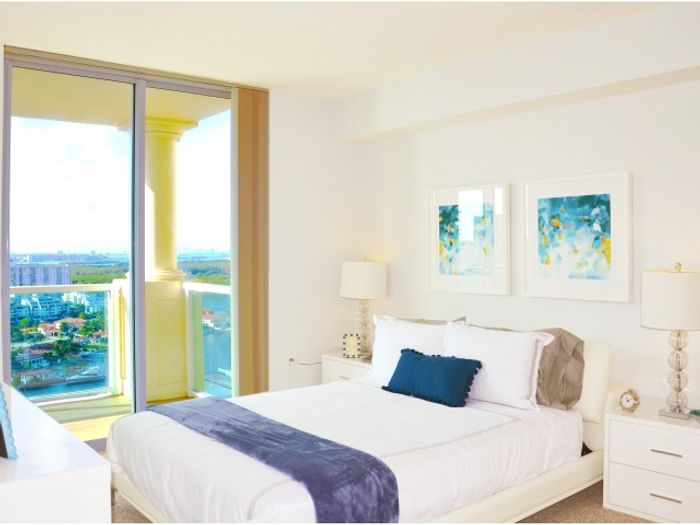 Intracoastal Yacht Club, interior, bedroom, large sliding glass door to balcony, bed, dresser, nightstands, lamps, view of the water