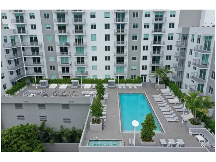 Brickell West City Rentals Exterior | Courtyard with pool | Pool chairs set up all around | Hot tub in corner of area