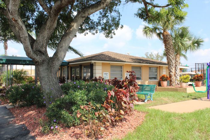 Pompano Palms Apartments, exterior, landscaping, building, park bench, outdoor exercise equipment.
