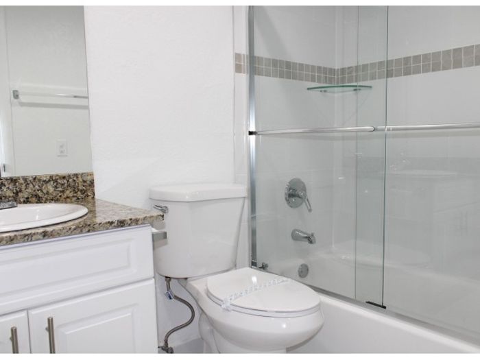Las Brisas Gardens Apartments, interior, white bathroom, shower/tub with sliding glass door, granite counter top, large mirror