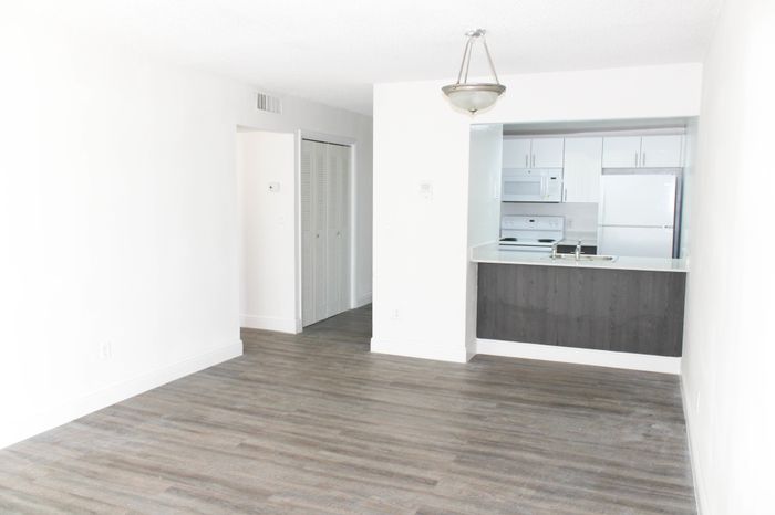 Inverrary 441 Apartments, interior, spacious living room, pass through counter to kitchen, white appliances, wood floor