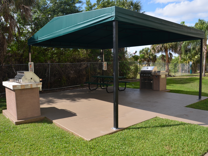 Royalton on The Green Exterior | Picnic area with grills | Green and yellow playground in background