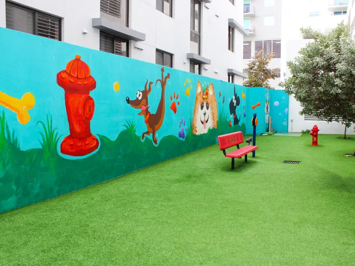 Brickell West City Rentals Exterior | Dog park | Painting of dogs on wall | Outdoor fake grass area | Bench