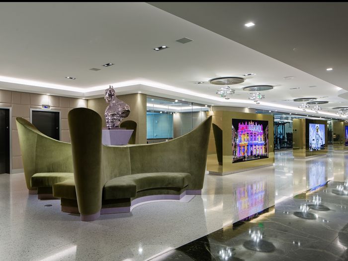Reflections Rentals Lobby Entrance, Large Green Couch with Silver Batman Bust on top, Elevators in the Back, and LightBoxes of various events and buildings