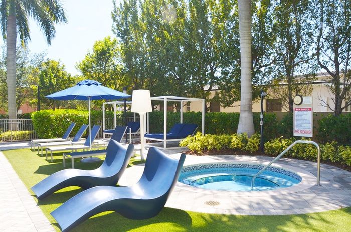 Gables 37 Grand, exterior, sparkling blue pool, palm trees, lounge chairs