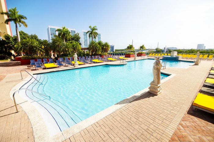 Intracoastal Yacht Club, exterior, sparkling blue pool, clubhouse, lounge chairs, statues