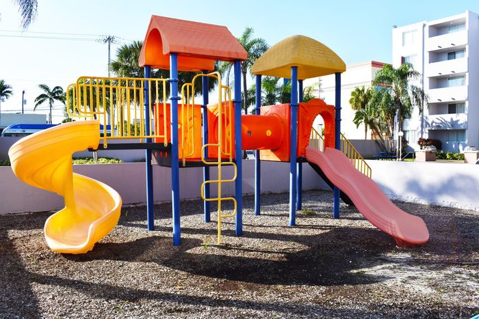 Suncoast Place Apartments- Outdoor play area- Bright orange and yellow colors- 2 slides- enclosed with a waist high barrier