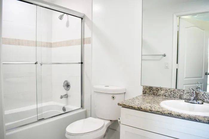 Bathroom with Granite Countertops and Tub with Glass Enclosure