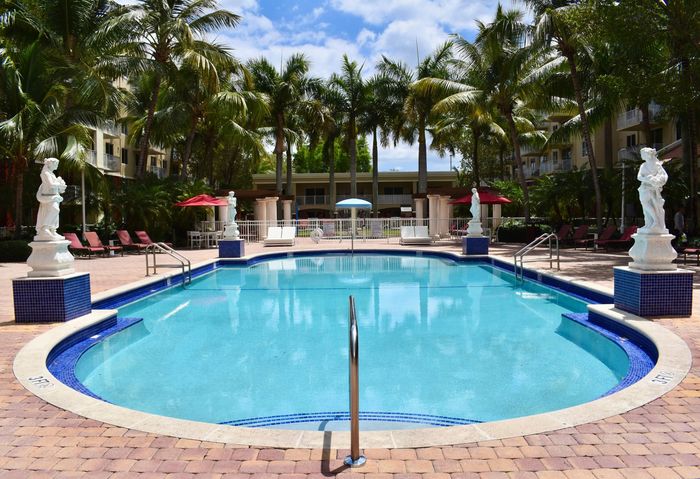Country Club Towers, exterior, sparkling blue pool, statues, palm trees, clubhouse