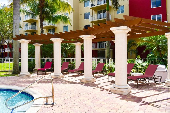 Lounge chairs under cabana, near kiddie pool, on pool deck, outside