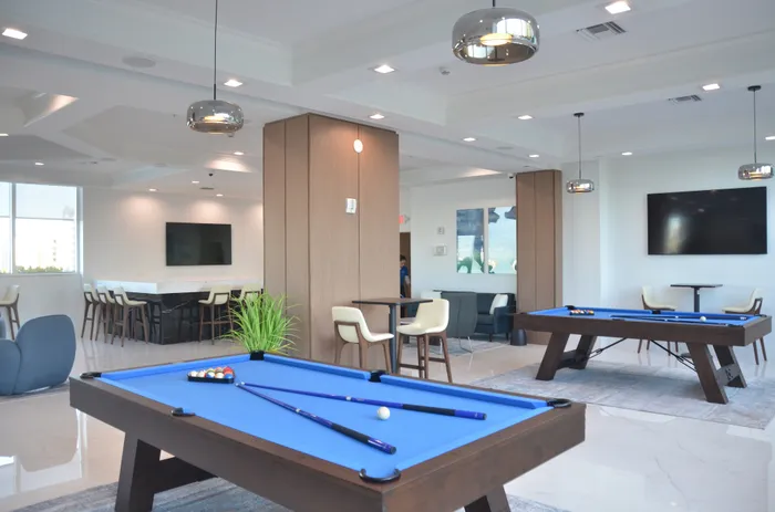 Elegant recreation area with pool tables, modern seating, and large TV screens.