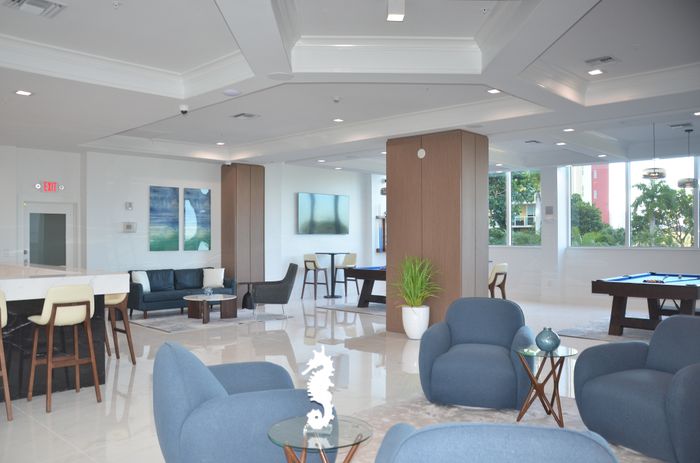 Elegant lounge featuring modern seating, a pool table, and large windows with lush views.