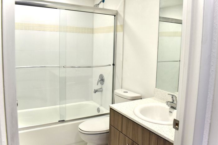 Bright modern bathroom featuring glass-enclosed bathtub, sleek vanity, and contemporary fixtures.