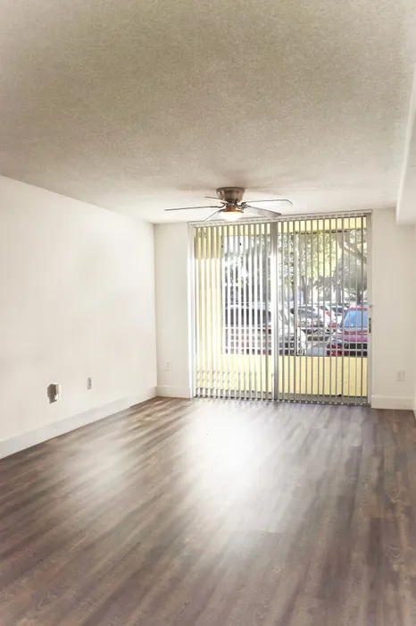 Modern open living room with hardwood floors, ceiling fan, and large sliding glass doors opening to a patio.