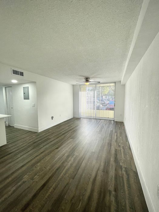Bright and spacious living area featuring elegant wood flooring and large sliding glass doors.