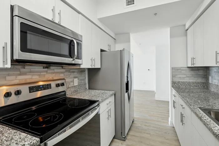 Modern kitchen with sleek stainless steel appliances, granite countertops, and stylish cabinetry, offering a fresh and contemporary space.