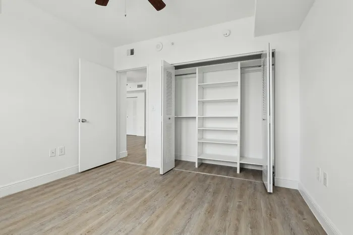 Contemporary bedroom with elegant hardwood flooring and a spacious built-in white closet.