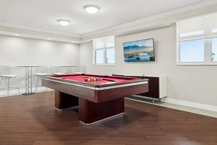 Elegant game room featuring a premium pool table, stylish seating against a modern backdrop, and a scenic wall-mounted display.