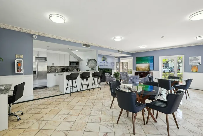 Modern open-concept community room featuring a sleek kitchen with stainless steel appliances, stylish bar seating, and elegant lounge area with contemporary decor.
