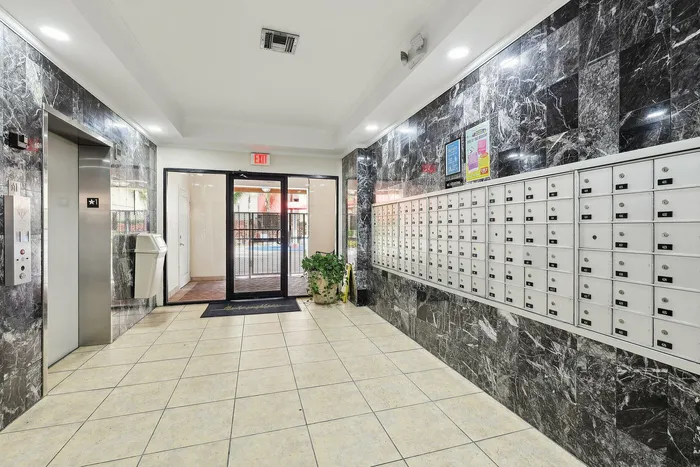 Modern apartment lobby with elegant marble walls, secure mailboxes, and sleek elevator access.