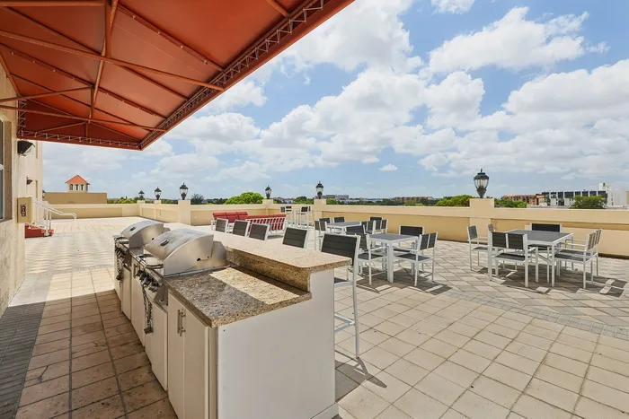 Chic rooftop terrace with stylish outdoor seating and BBQ grills under a vibrant canopy, offering stunning city views.