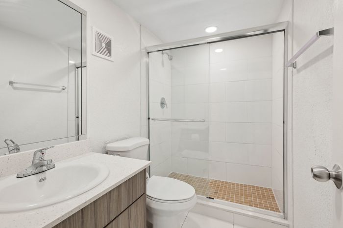 Modern bathroom featuring sleek fixtures, a spacious glass-enclosed shower, and elegant wood cabinetry.
