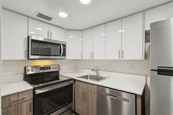 Sleek modern kitchen with gleaming stainless steel appliances, pristine white cabinetry, and stylish countertops.
