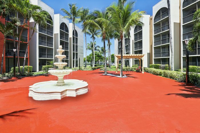 Vibrant apartment complex courtyard featuring a charming fountain, lush palm trees, and modern architecture.