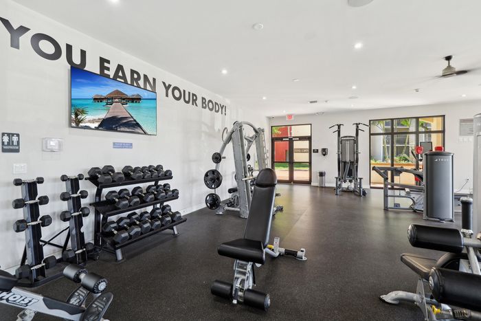 Modern fitness center with state-of-the-art gym equipment, motivational wall art, and large windows offering garden views.