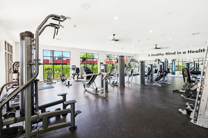 Bright, spacious gym with modern fitness equipment and large windows overlooking greenery, promoting an active lifestyle.