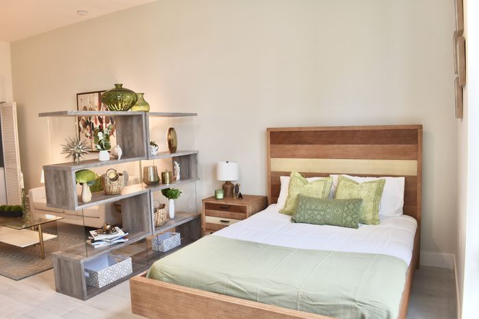 Elegant bedroom with modern wooden furniture, soft green accents, and decorative shelving, creating a cozy and stylish living area.