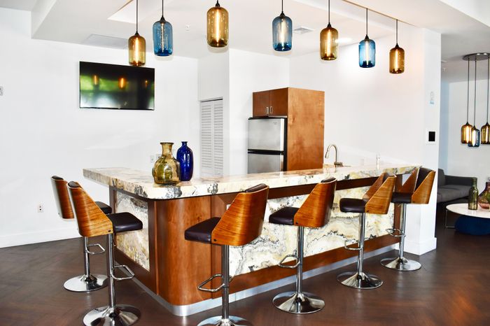 Elegant modern kitchen featuring a sleek marble countertop, stylish pendant lighting, and chic bar stools.