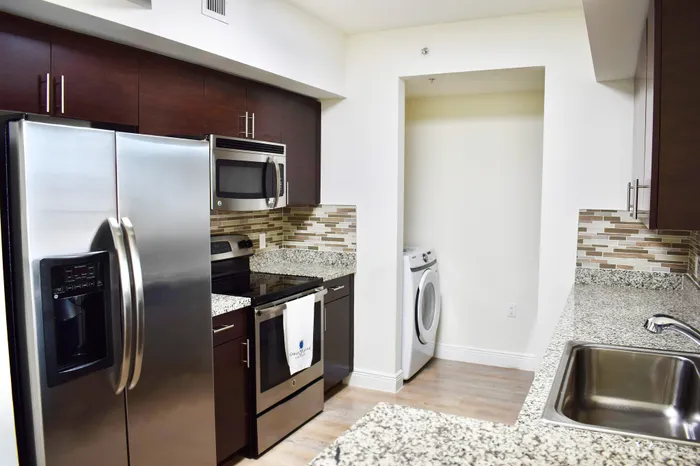 Modern kitchen with sleek stainless steel appliances, elegant dark cabinetry, and stylish granite countertops, seamlessly blending functionality and aesthetics.